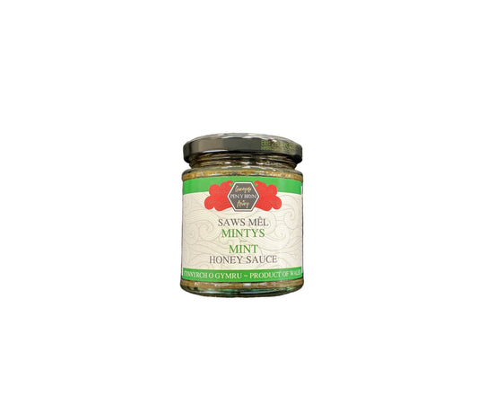 A glass jar of Saws-Mêl Mintys Mint Honey Sauce with a black lid and white label, placed on a dark textured surface.